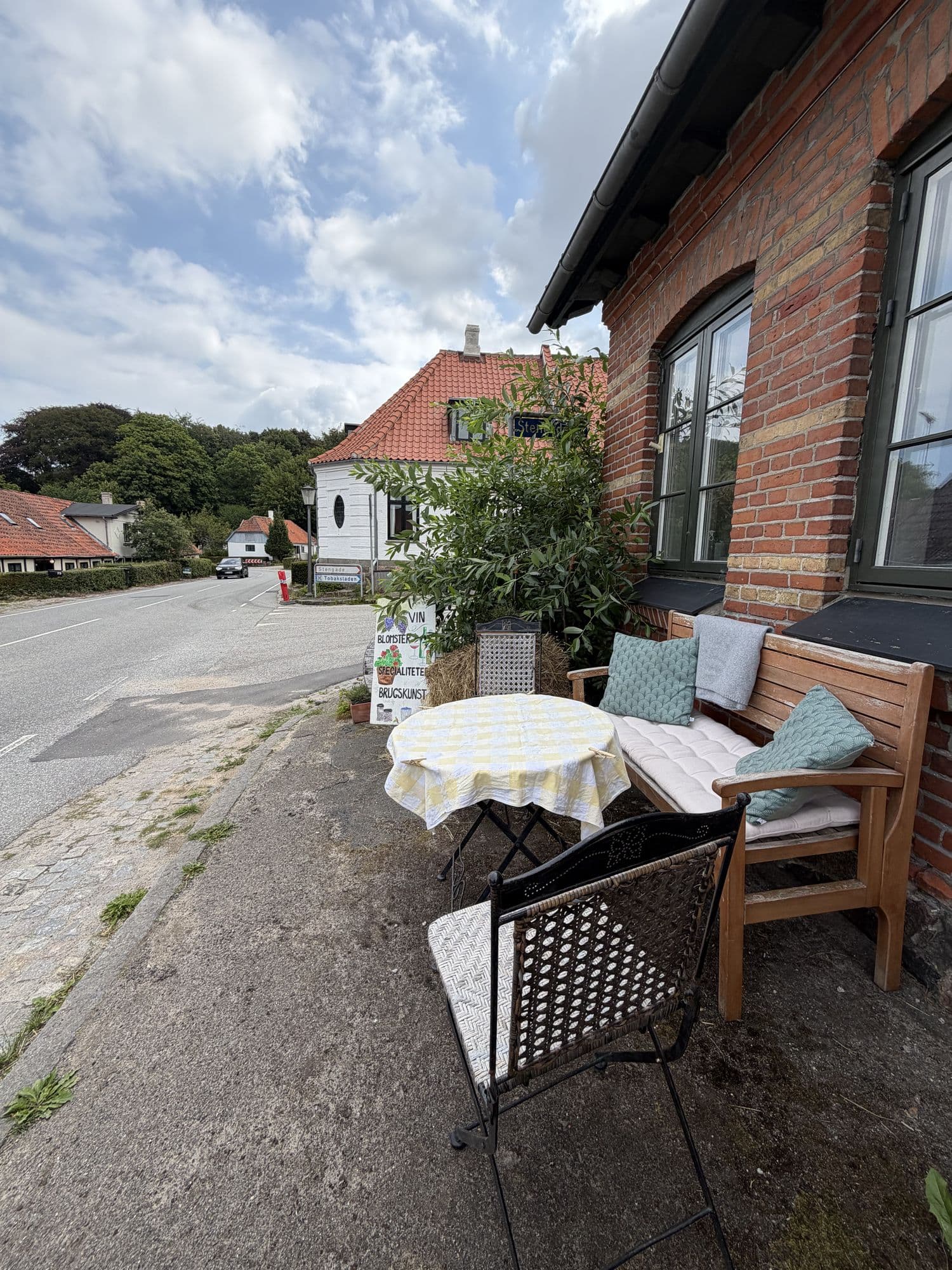 Skilt med "Vin, blomster, specialiteter, brugskunst" foran butikken
