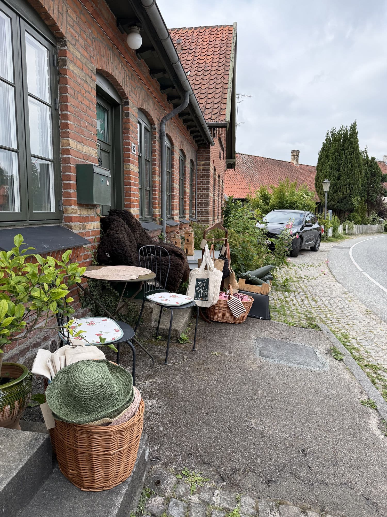 Udendørs siddeplads med kurve og tasker foran butikken