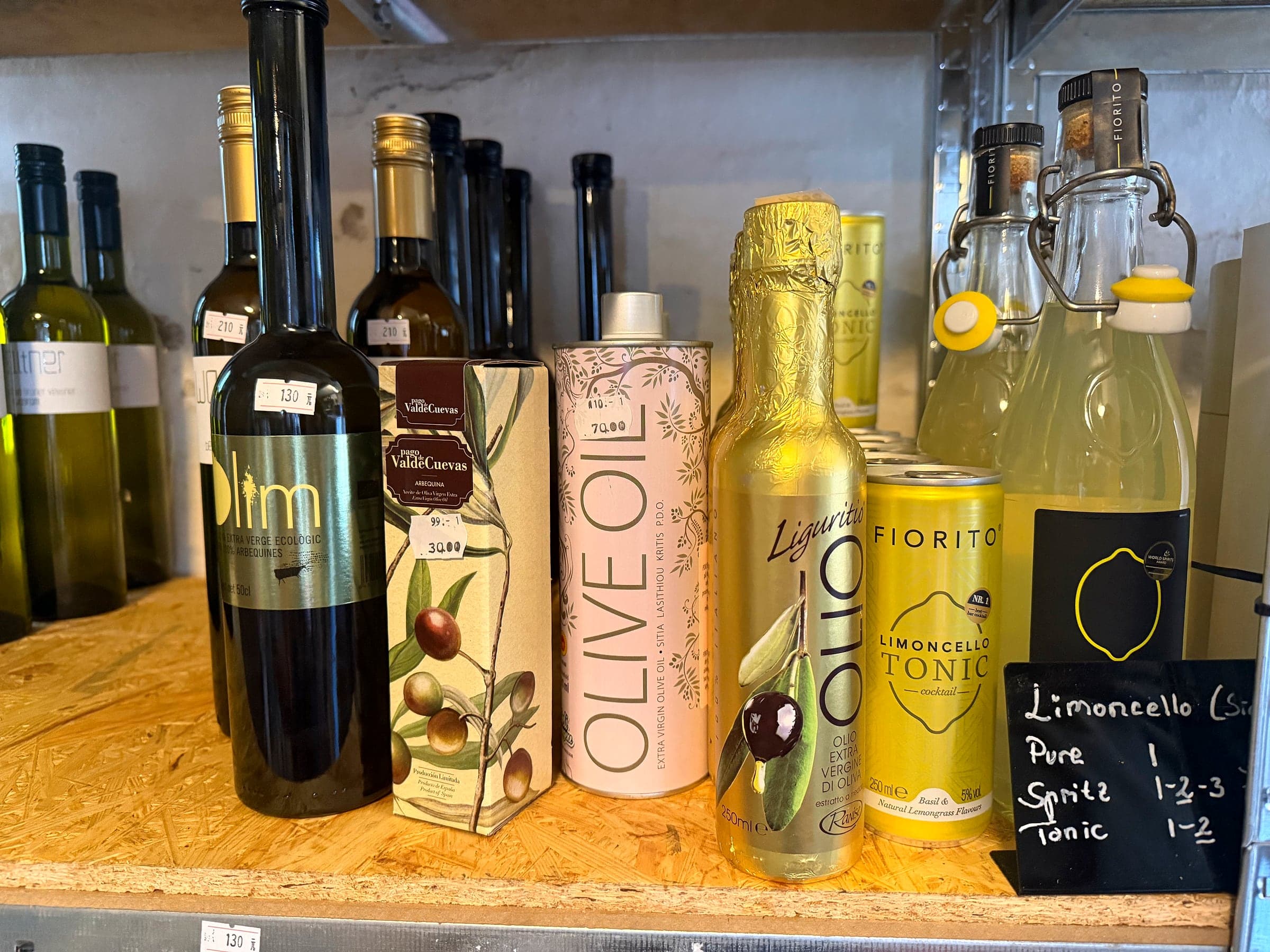 Olivenolie, limoncello og tonic ved siden af hinanden på hylden