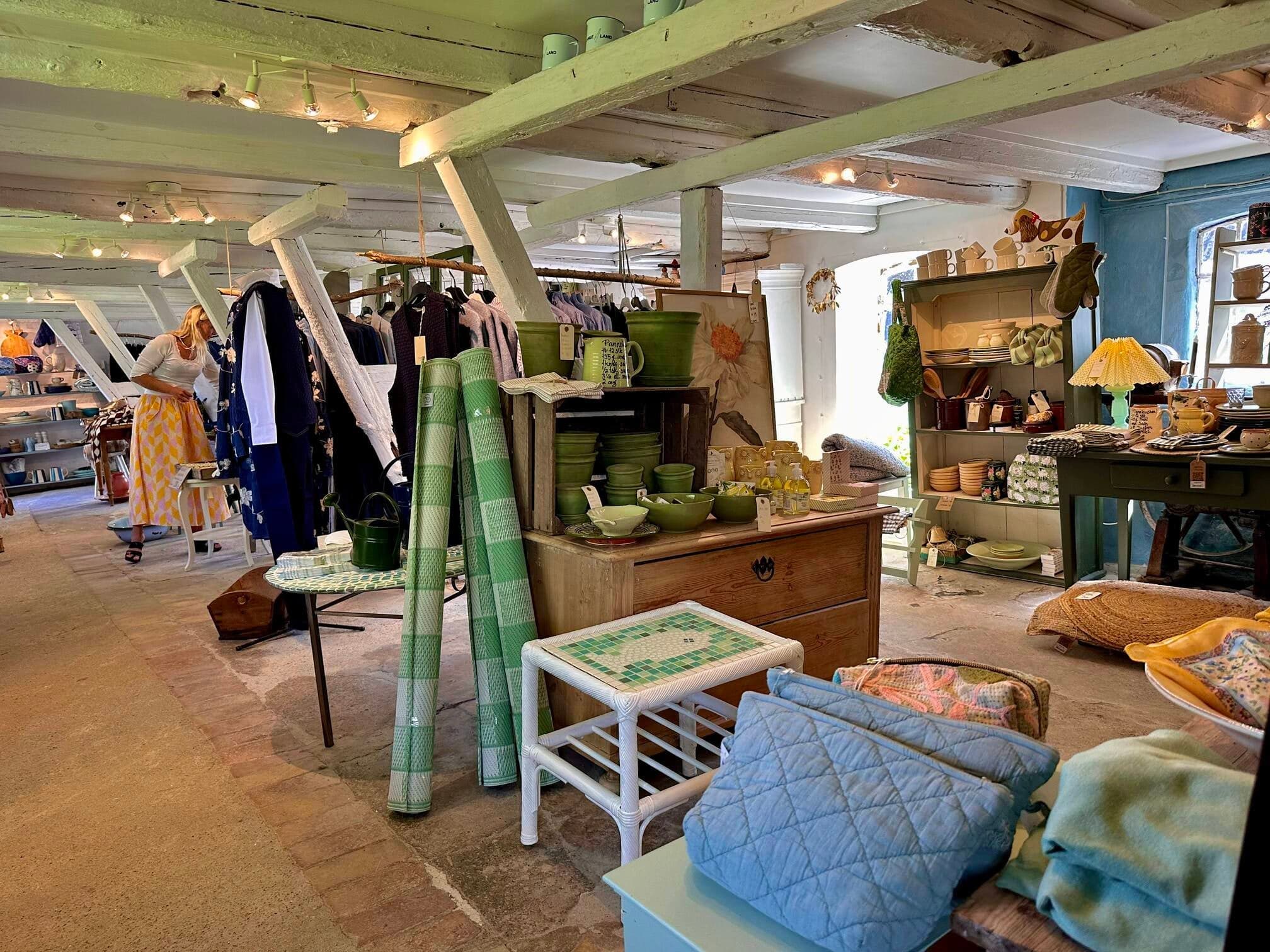 Butiksrum med grønne krukker, tøj og en kunde, der kigger på varerne