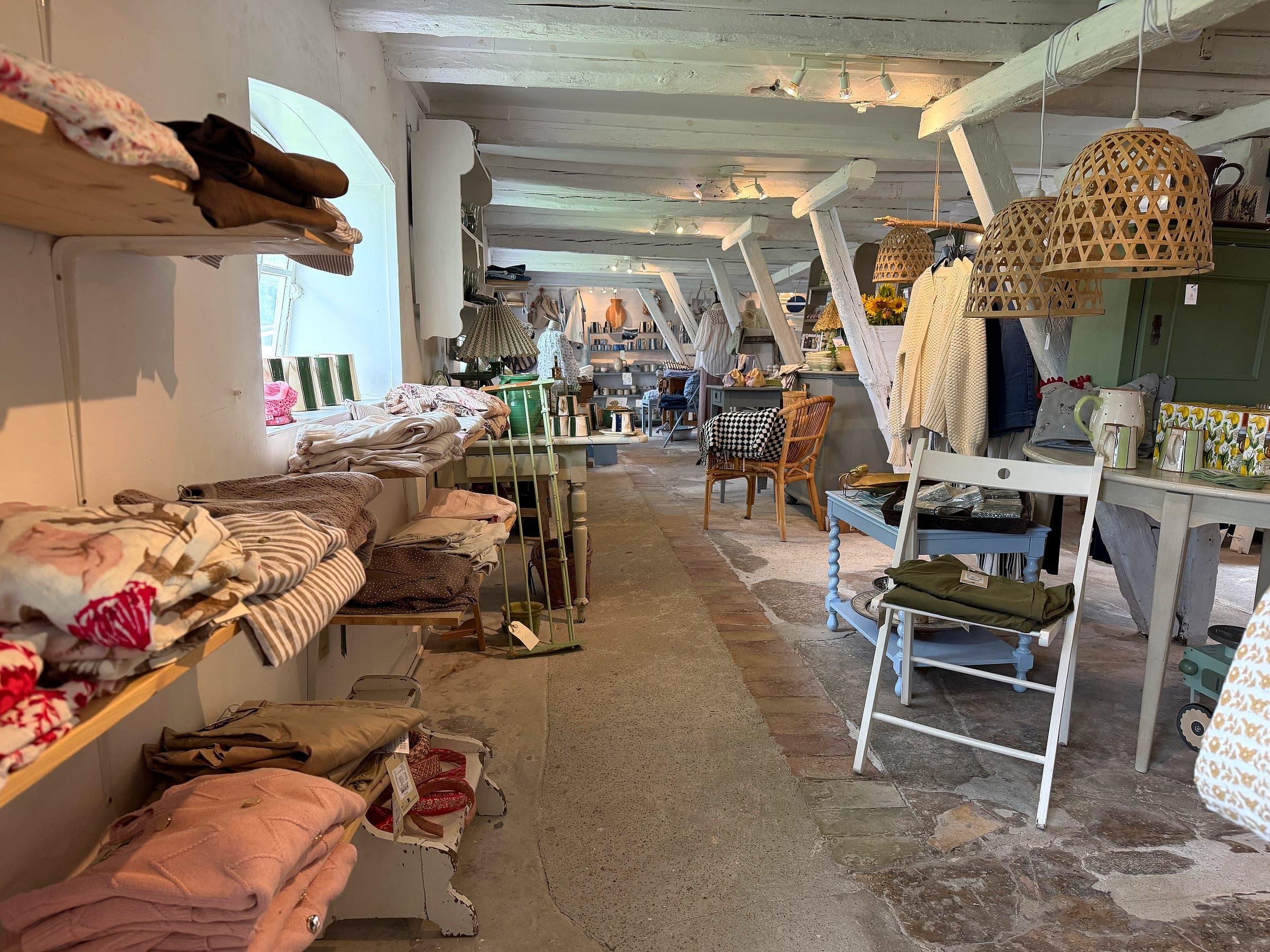 Butikken hos Himmel og Hav med tøjstativer, keramik og hyggelige loftslamper