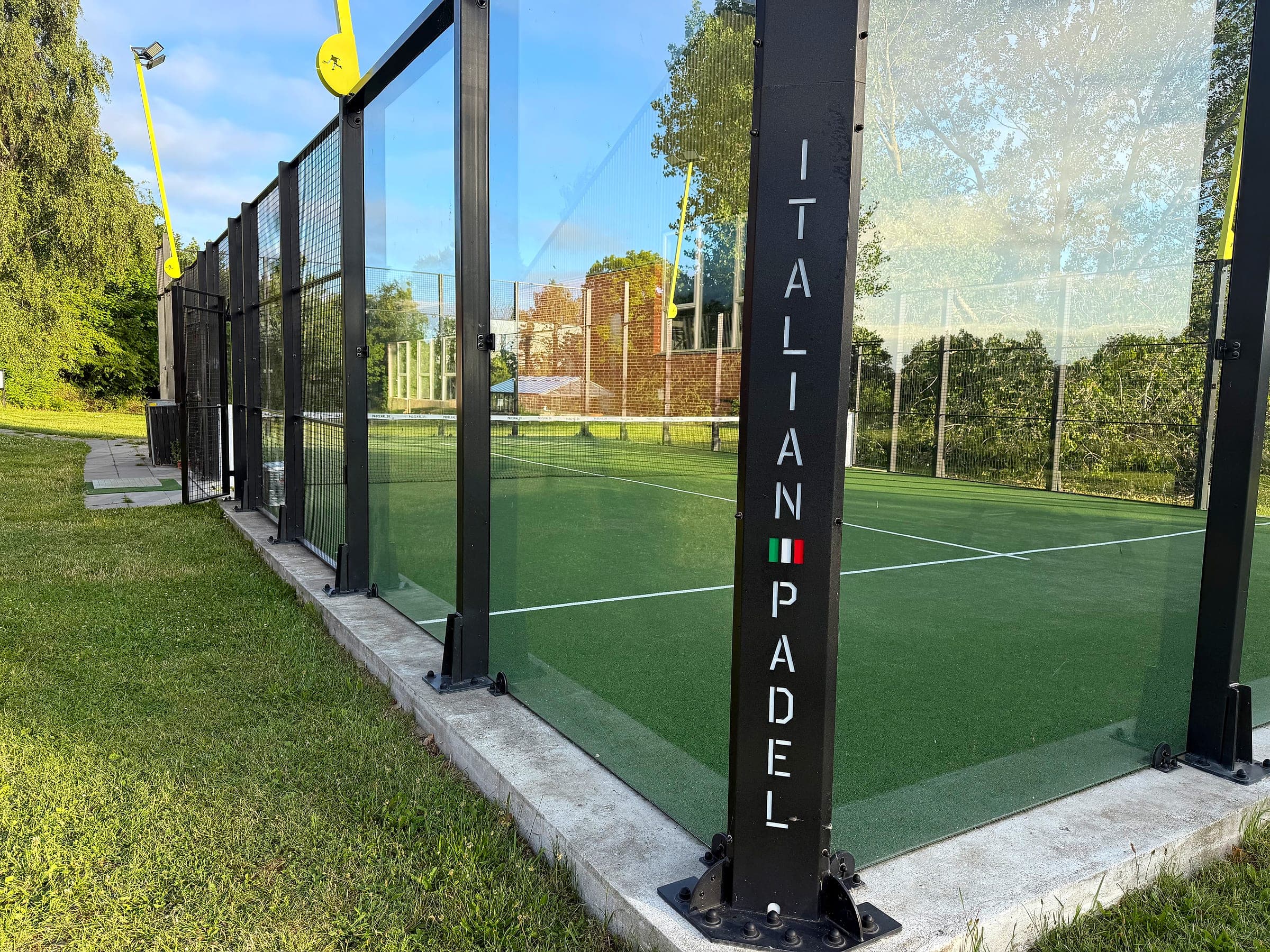 Nærbillede af glasvæggen på padelbanen med teksten Italian Padel
