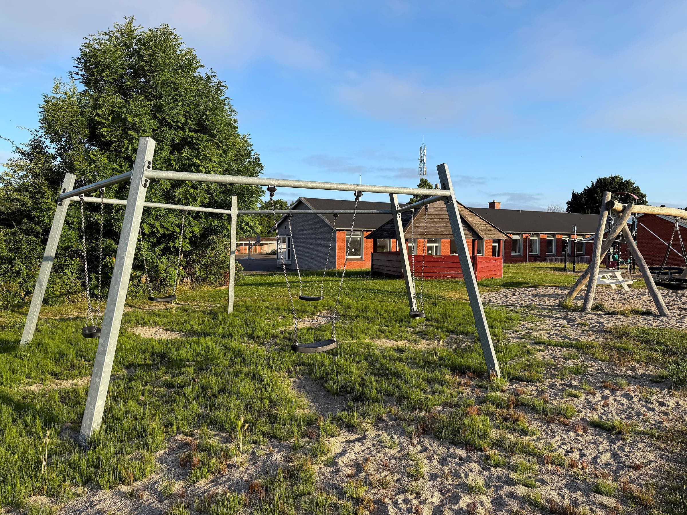 Gyngestativ med flere sæder, med Nordlangelandshallen i baggrunden