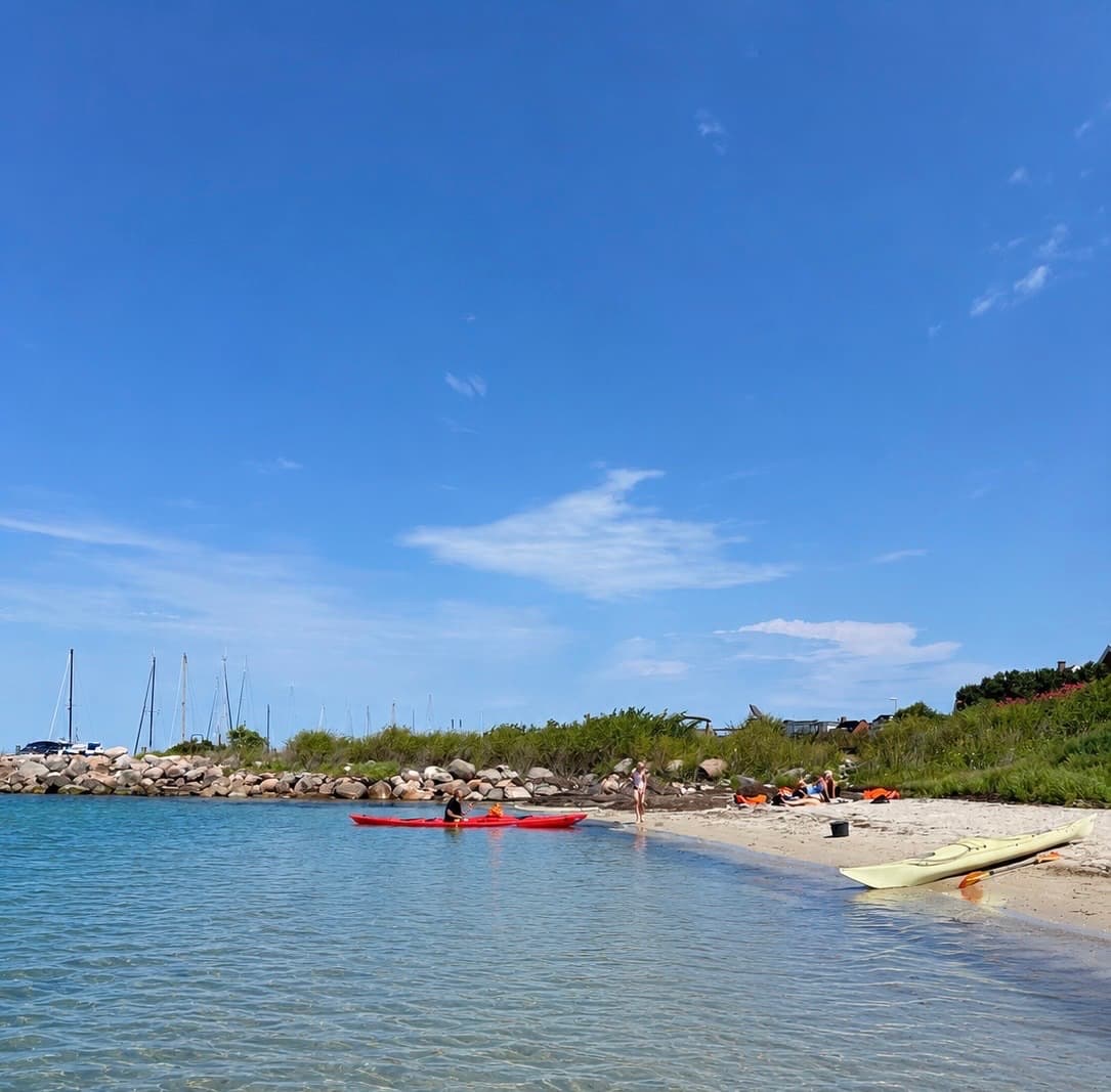 Kajakker på sandet ved Lille Strand med Lohals Havn i baggrunden